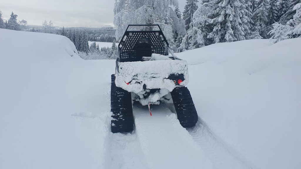 En ATV står på en ubrøytet skogsbilvei.