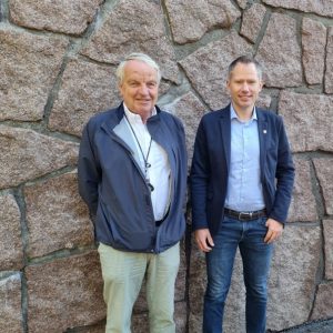 Bilde: to menn står mot en murvegg